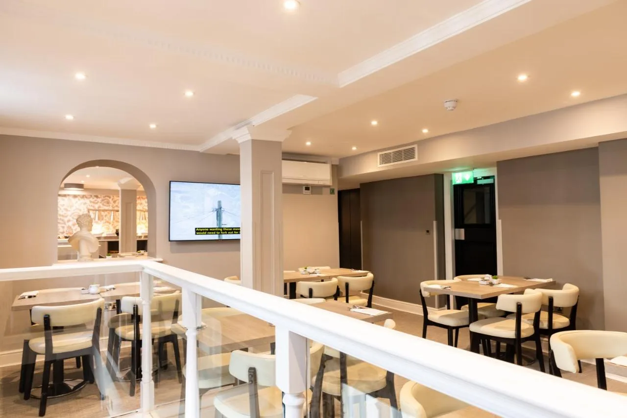 a restaurant with tables and chairs and a screen at Byron Hotel in London