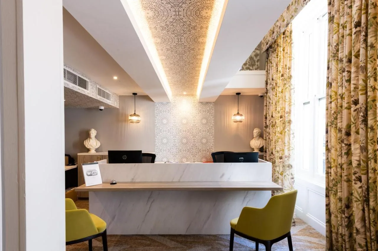 a lobby with a reception desk and chairs at Byron Hotel in London