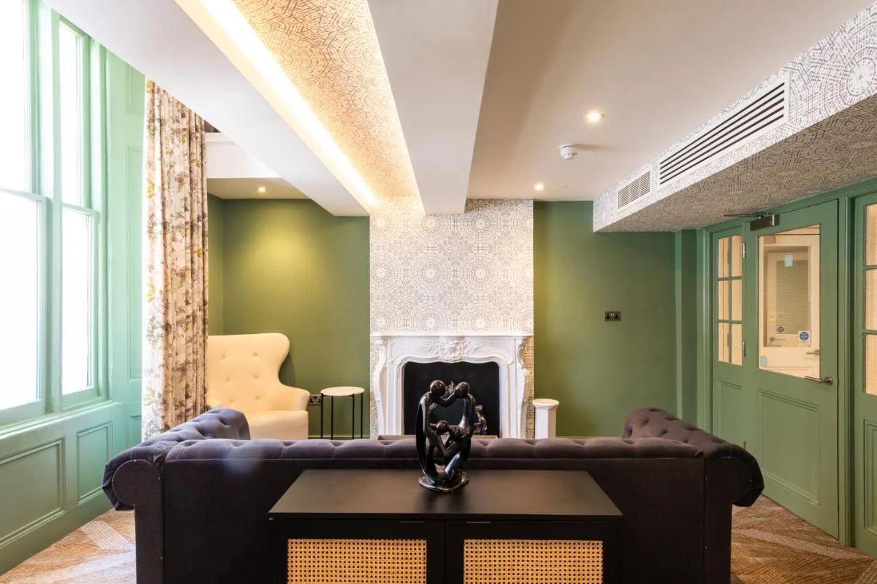 a living room with a couch and a fireplace at Byron Hotel in London